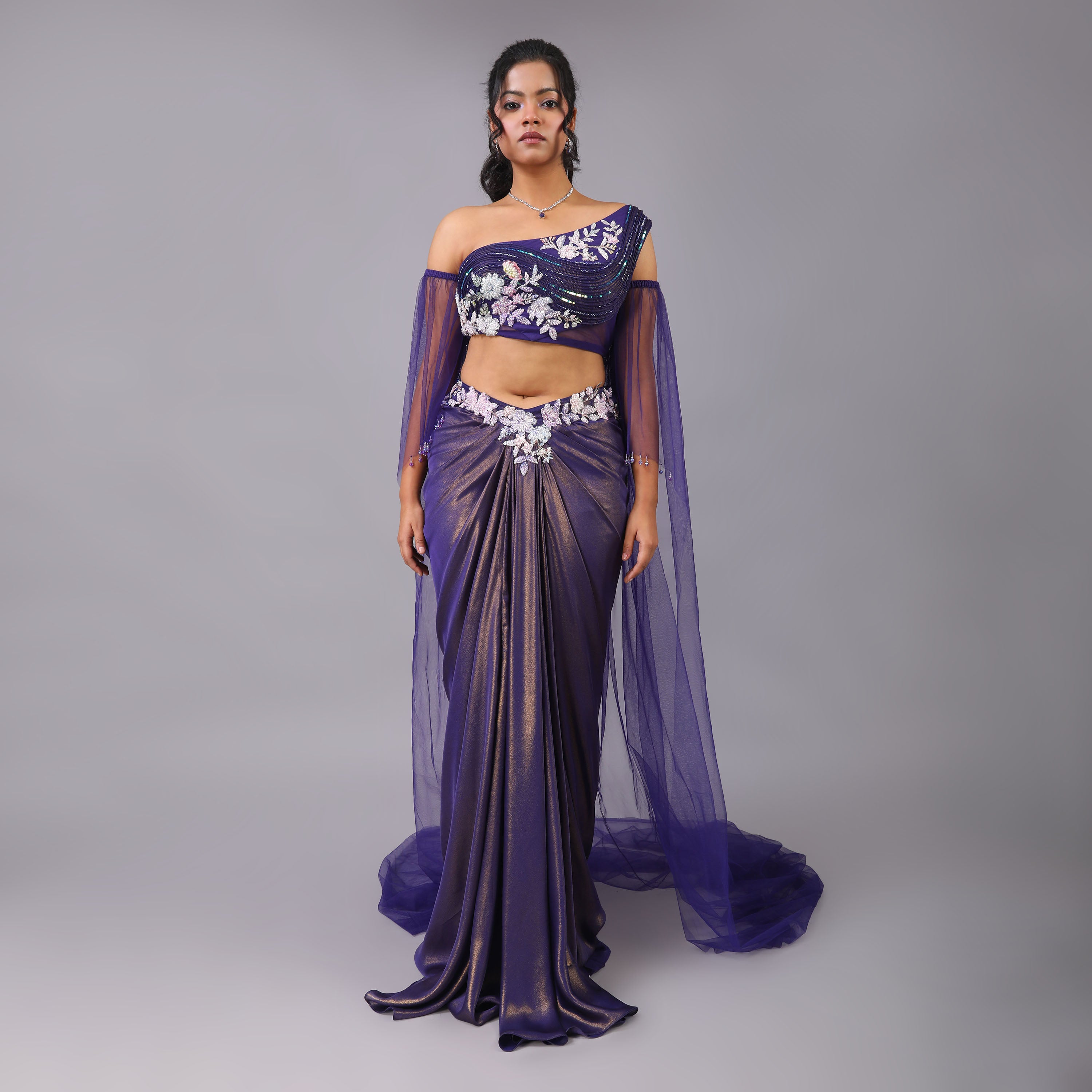 Shimmering Purple Draped Skirt with Sculpted One-Shoulder Blouse and Sheer Trailed Cape