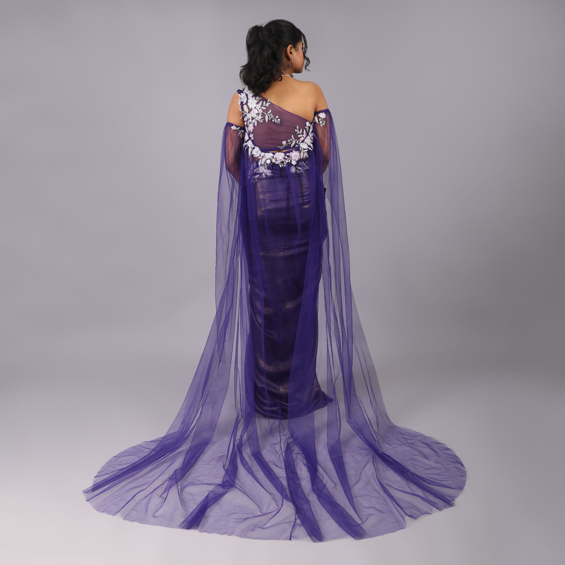 Shimmering Purple Draped Skirt with Sculpted One-Shoulder Blouse and Sheer Trailed Cape